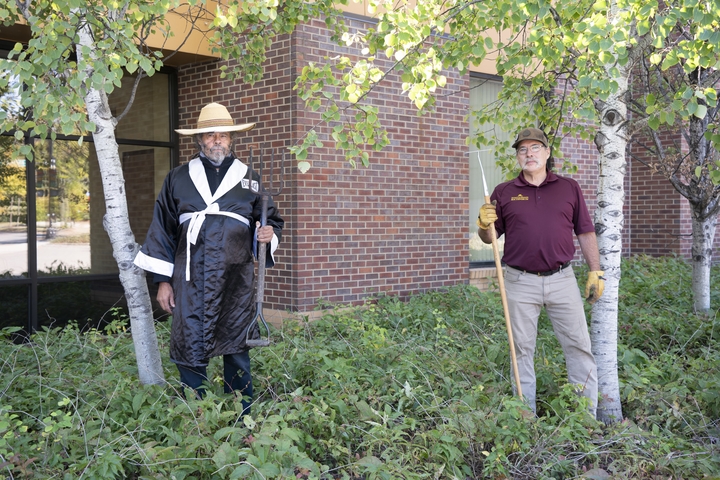Karl Hakanson and Michael Chaney pose with gardening tools outside the UROC building