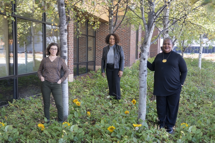 Lauren Martin, Artika Roller, and Reverend Alika Galloway stand by trees outside the UROC building