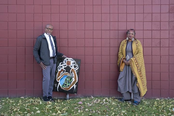 Christopheraaron Deanes and Hawona Sullivan Janzen stand next to a brick wall